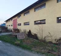 An industrial building in Ladce with yellow walls and stacked wooden pallets.