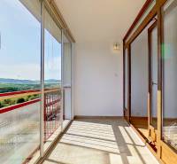 Glazed balcony with a view in a 4-room apartment with red railings.