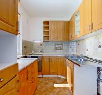 A kitchen in a 4-room apartment with wooden cabinets and ceramic tiles.