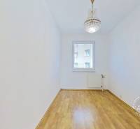 An empty room in a 4-room apartment with white walls and parquet flooring.
