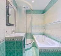 Bathroom of a 4-room apartment with a shower, bathtub, and tiles in green and white tones.