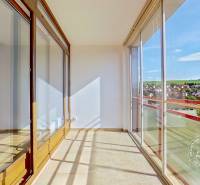 A glazed terrace in a 4-room apartment with a view of the surroundings through large windows.
