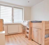 Wooden bed with a desk, cabinets, window with blinds, light flooring. 3-room apartment.