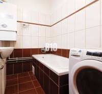 Bathroom in a 3-room apartment with a bathtub, washing machine, and sink.