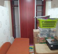 A narrow space with an orange couch, cabinets, and stored boxes in a 2-room apartment.