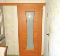 Wooden sliding doors in the entrance of a 2-room apartment with patterned wallpaper.
