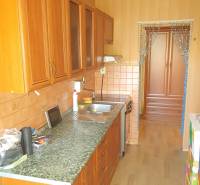 A kitchen in a 2-room apartment with wooden cabinets and tiled backsplash.