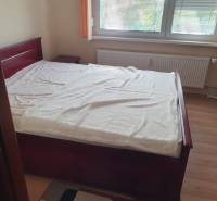 A bedroom in a two-room apartment with light wooden furniture and a window with blinds.