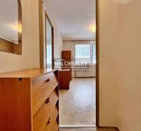 Studio apartment with a wooden dresser and a mirror, view of the room with windows.