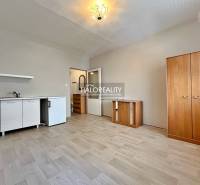 A studio apartment with a light interior, wooden flooring, and furniture in neutral colors.