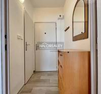 Hallway in a studio apartment with a dresser, mirror, and white walls.