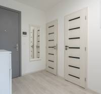 Entrance hallway in a 3-room apartment with a mirror, white furniture, and light-colored doors.