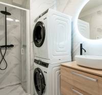 Bathroom with a washing machine, dryer, shower corner, and sink in a 3-room apartment.