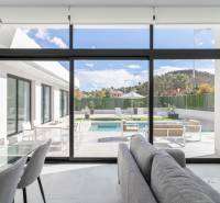 The interior of the villa with large glass doors leading to the terrace with a pool.