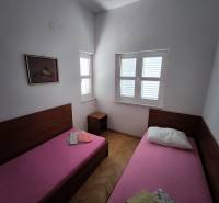 Two single beds side by side in a studio apartment, bright room with wooden floors.