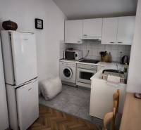 A kitchen in a studio apartment with white cabinets, appliances, and a wooden table.