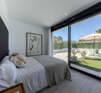 A bedroom in a villa with large windows and a view of the garden.