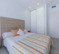 Bright bedroom in a villa with minimalist furniture, textile accessories, and a built-in wardrobe.
