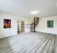 Living room in a family house with wooden stairs and artistic paintings on the walls.
