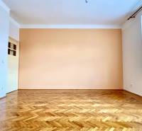 An empty room with a parquet floor and a large window in a two-room apartment.