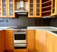A kitchen in a 2-room apartment with wooden cabinets and dark tiles.