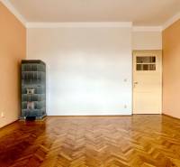 A room with a parquet floor and a tiled stove in a two-room apartment.