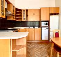 A kitchen in a 2-room apartment with wooden cabinets, a dining table, and parquet flooring.