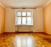 A room with parquet flooring and a large window illuminates the interior of a 2-room apartment.