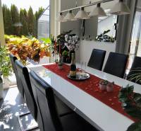 A dining room in a family house with plants, a set table, and a view of the garden.