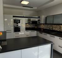A kitchen in a family house with white cabinets and black and white mosaic tiles.