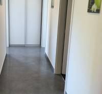 A hallway in a family house with tiles, light-colored walls, and pendant lighting.