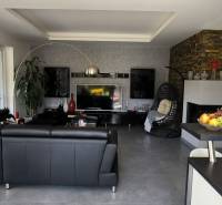 Living room in a family house with black sofa furniture and a TV on the wall.