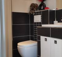 A bathroom in a family house with black and white tiles and a toilet.