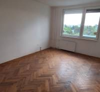 A room in a 3-bedroom apartment with a parquet floor and a large window.