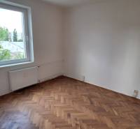 An empty room with a parquet floor and a window in a 3-room apartment.