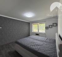 A bedroom in a family house with an upholstered bed and a gray wall.