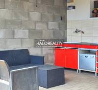 Seating and kitchenette in the gardens in Lučenec. Rattan furniture and a red cabinet.