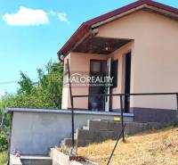 A house with a garden in Lučenec, surrounded by greenery and a blue sky.
