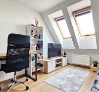 A desk with a black chair, a television, and a shelf in a 4-room apartment.