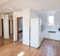A kitchen with white cabinets and appliances in a 4-room apartment with wooden flooring.
