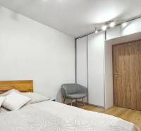 A bedroom with a bed, an armchair, and a built-in wardrobe in a 4-room apartment.