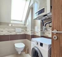 Bathroom in a 4-room apartment with a washing machine, suspended toilet, and skylight.