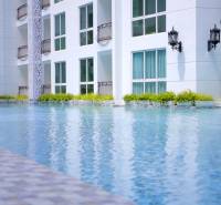 Apartment construction in Pattaya with landscape architecture and a pool in the background of the buildings.