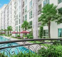 Construction of apartments in Pattaya with a swimming pool, palm trees, and an apartment complex for sale.