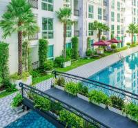 Apartment construction in Pattaya with a swimming pool, greenery, balconies, and outdoor relaxation areas.