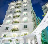 A building under construction of apartments in Pattaya with a white facade and balconies with plants.
