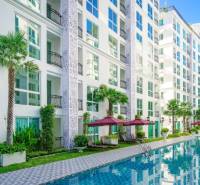Apartment construction in Pattaya: White apartment complex with palm trees and a swimming pool.