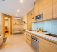 A kitchen in a 3-room apartment with wooden cabinets, a television, and a view of the living room.