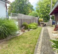 A garden at a family house in Koválov with a walkway, greenery, and wooden furniture.