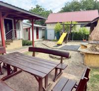 The garden of a family house in Koválov: wooden furniture, fireplace, slide, and swing.
